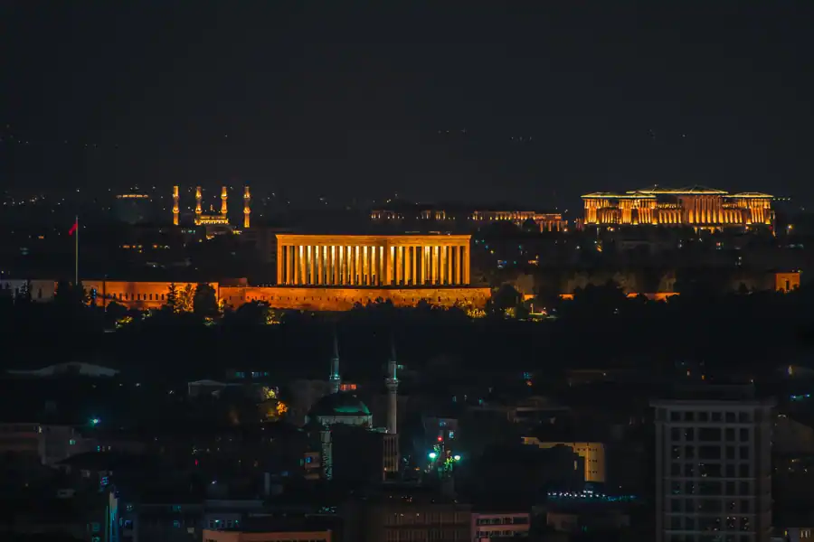 Illuminated Anıtkabir at night in Ankara cityscape, showcasing iconic architecture.