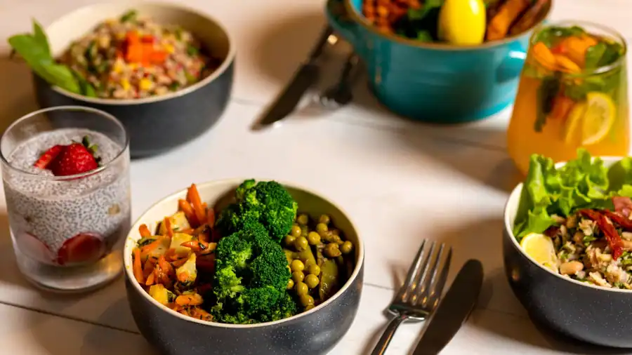 Delicious colorful bowls of salad and fresh beverages on a white table, perfect for healthy dining.