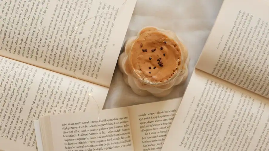 A comforting setup with a cappuccino and open books from above view.