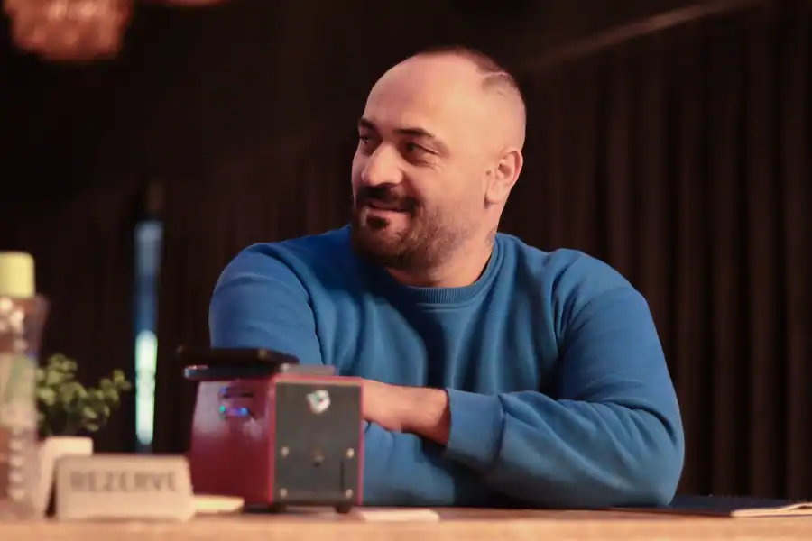 Casual portrait of a man in a blue sweater sitting indoors at a restaurant.