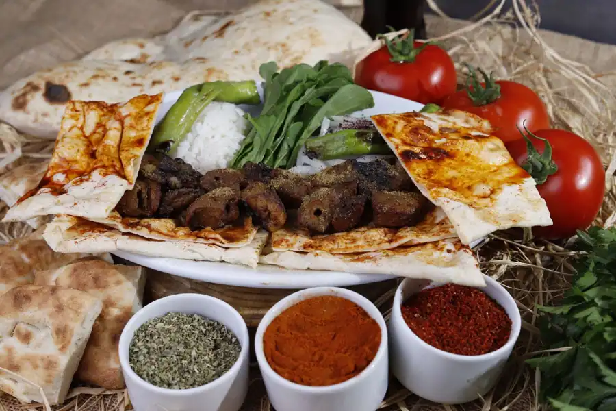 Savory Turkish kebab served with fresh vegetables, spices, and bread, showcasing a traditional culinary delight.